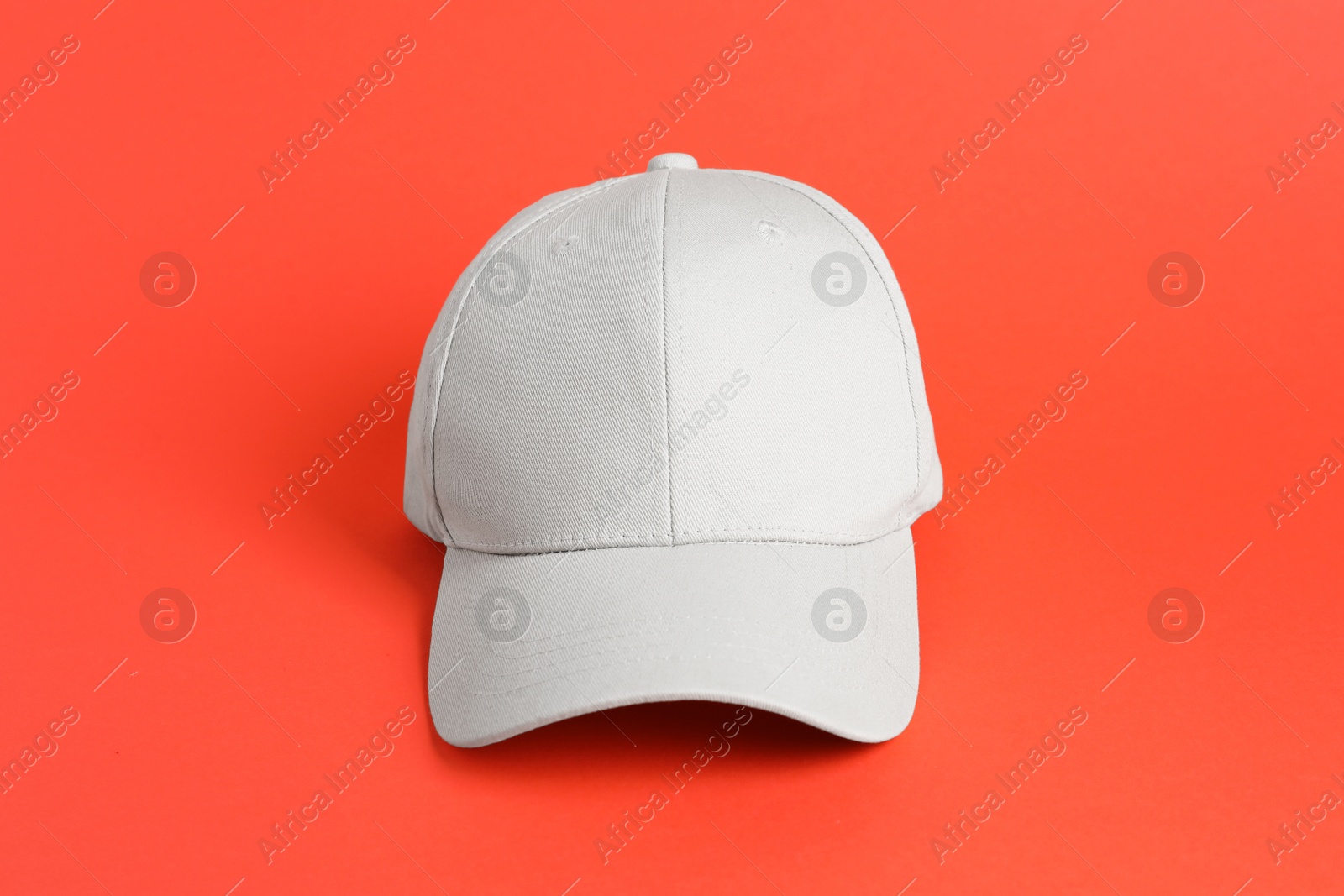 One beige baseball hat on coral background Photo of One beige baseball hat on coral background