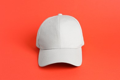 Photo of One beige baseball hat on coral background