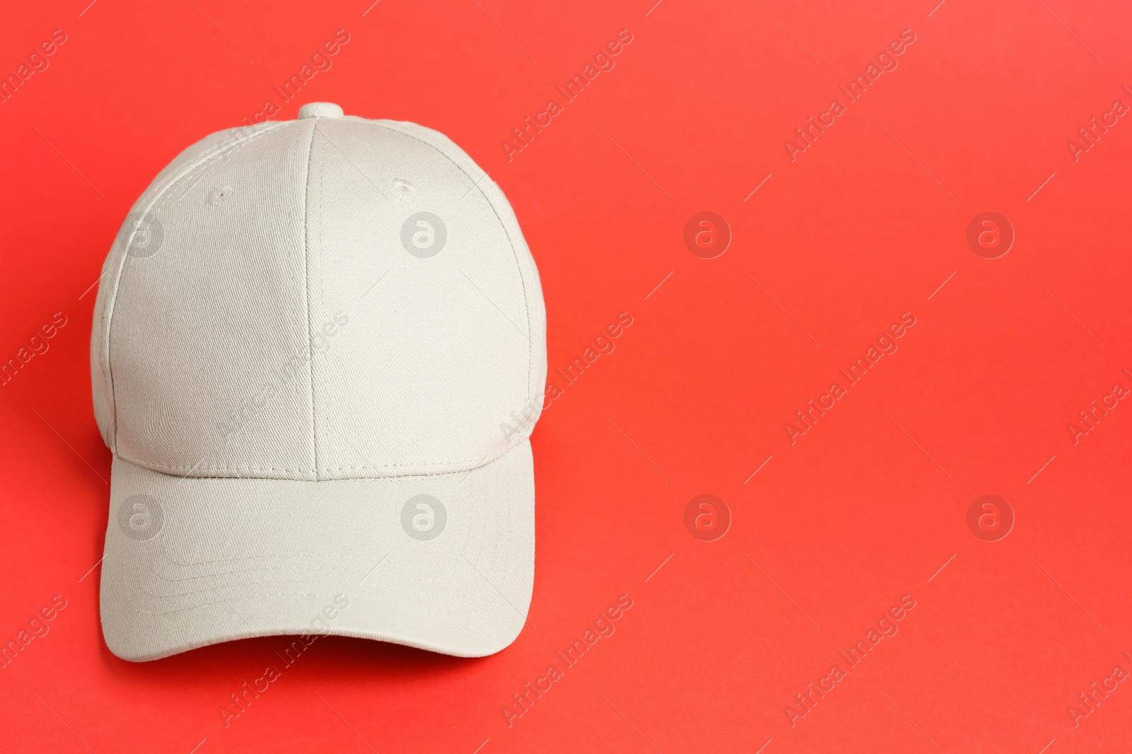 Beige baseball hat on coral background, space for text Photo of Beige baseball hat on coral background, space for text
