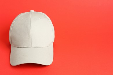 Photo of Beige baseball hat on coral background, space for text