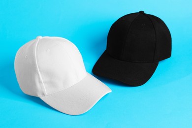Photo of White and black baseball hats on light blue background