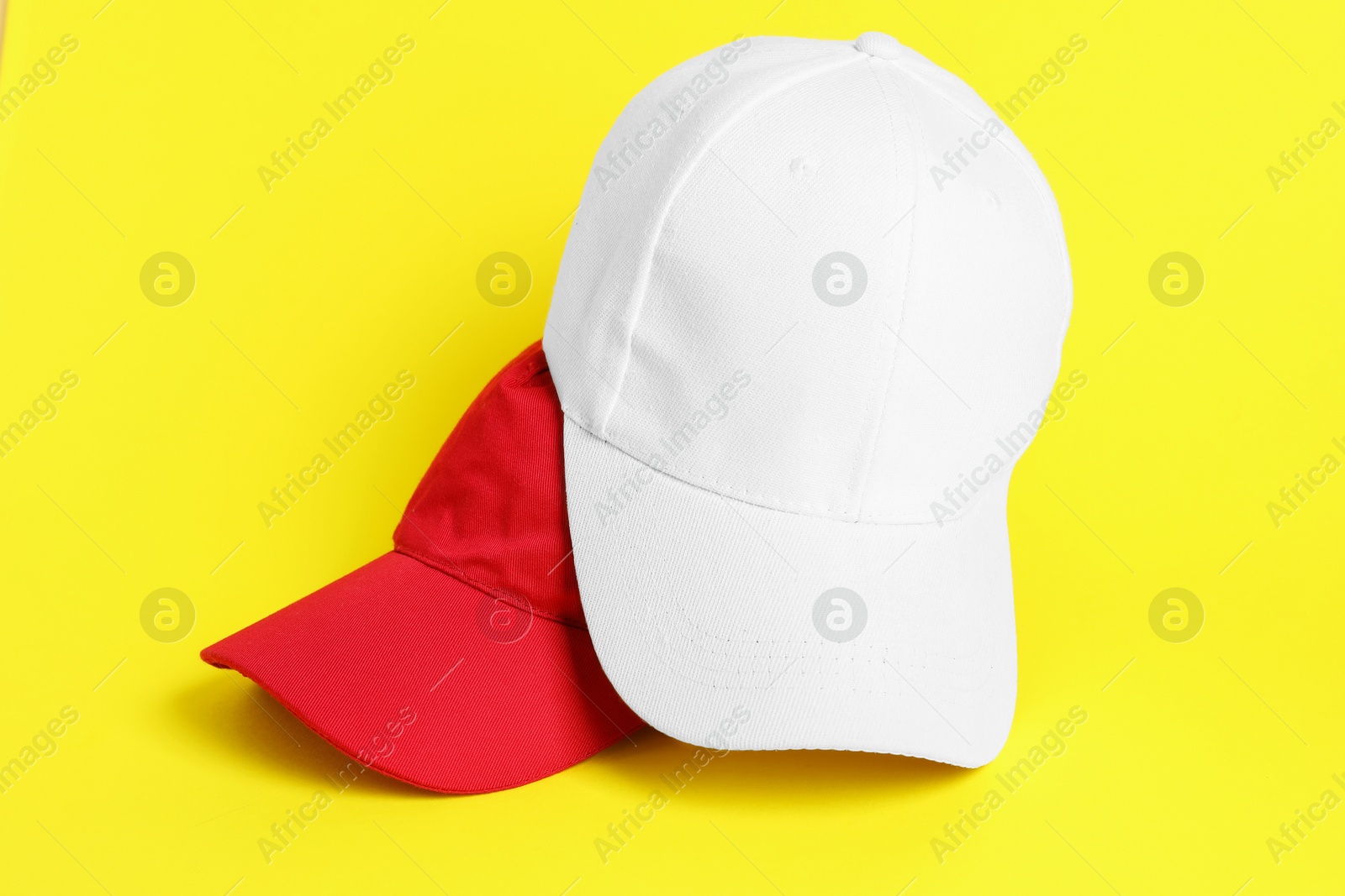 Photo of White and red baseball hats on yellow background