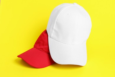 Photo of White and red baseball hats on yellow background