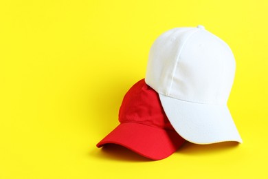 Photo of Colorful baseball hats on yellow background, space for text