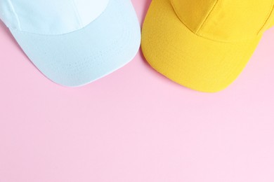 Photo of White and yellow baseball hats on pink background, top view. Space for text