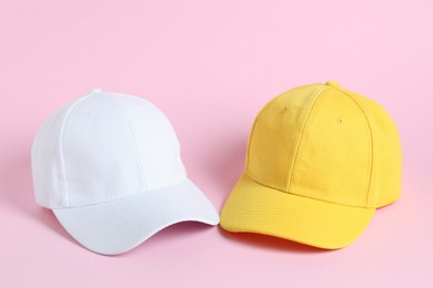 Photo of White and yellow baseball hats on pink background