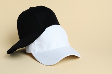 Photo of Black and white baseball hats on pale yellow background