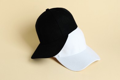 Photo of Black and white baseball hats on pale yellow background