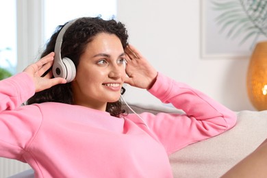 Photo of Young woman with headphones listening to music at home