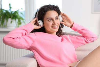 Photo of Young woman with headphones listening to music at home