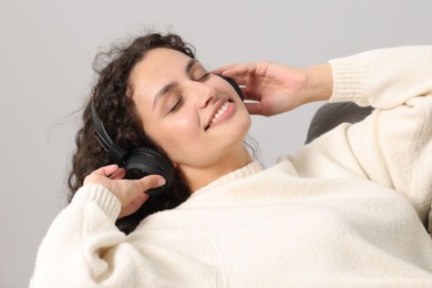 Photo of Young woman with headphones listening to music on armchair at home