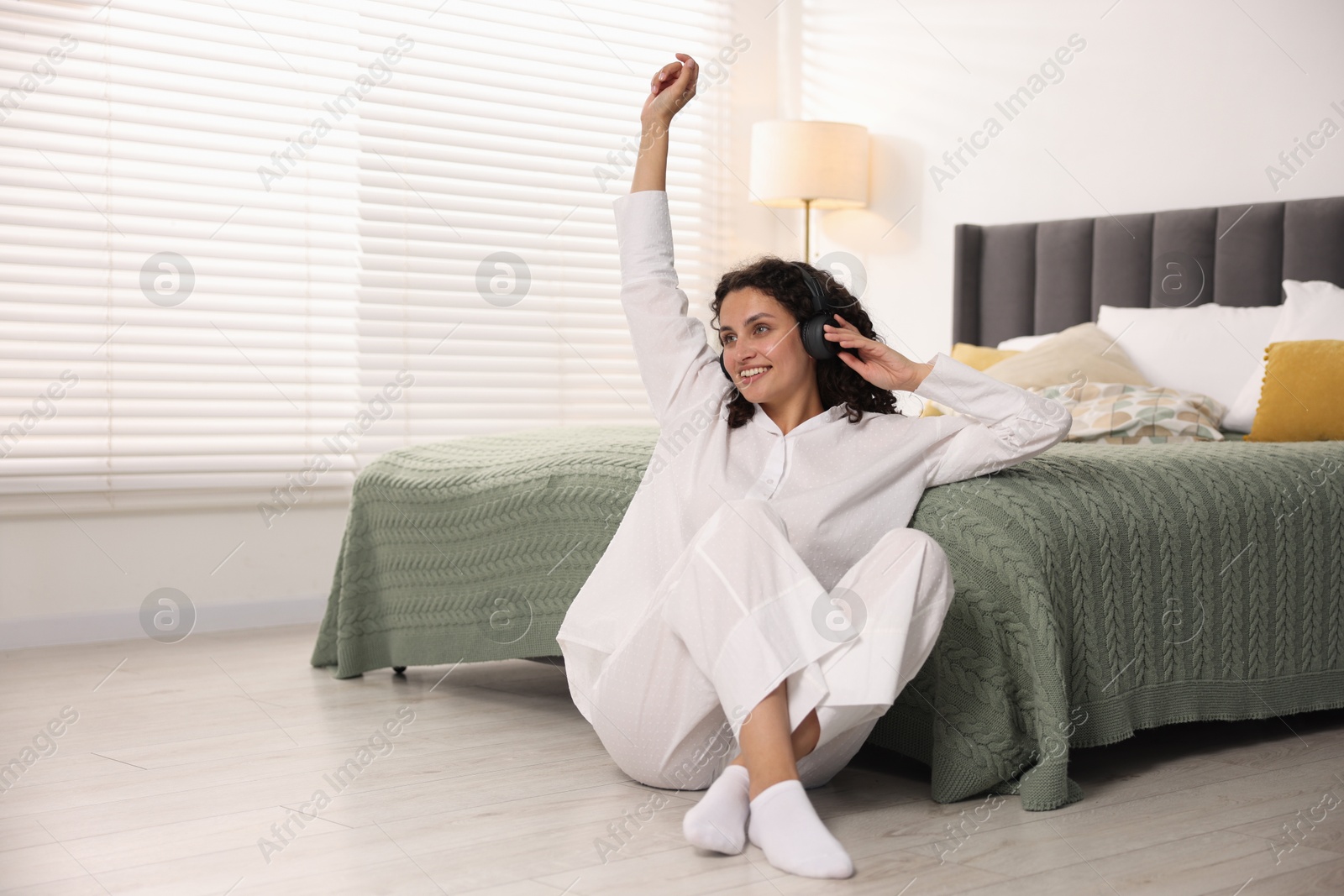 Photo of Young woman with headphones listening to music at home, space for text