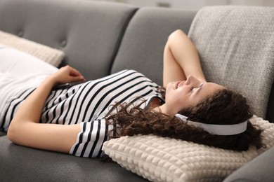 Photo of Young woman with headphones and smartphone listening to music at home