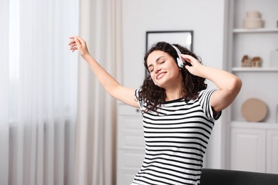 Photo of Young woman with headphones listening to music at home