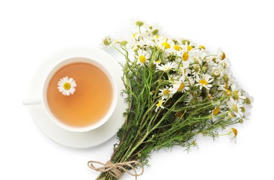 Photo of Aromatic tea in cup and chamomile flowers isolated on white, top view