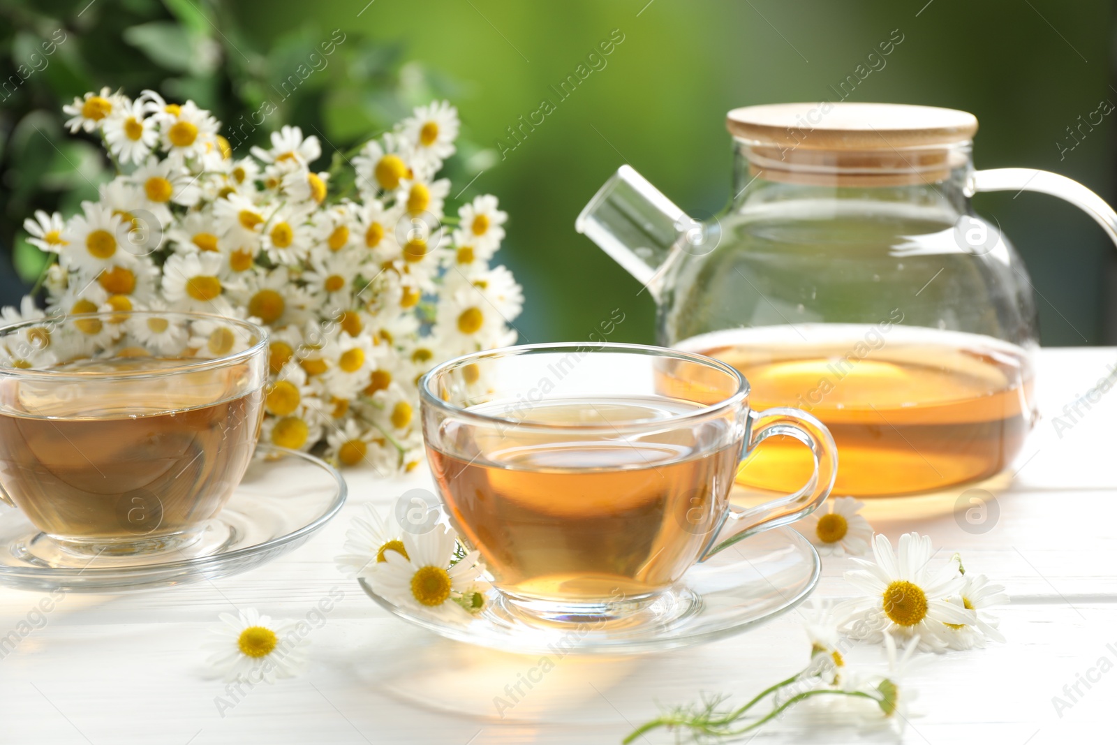 Aromatic tea in glass cups and chamomile flowers on white wooden table, closeup Photo of Aromatic tea in glass cups and chamomile flowers on white wooden table, closeup