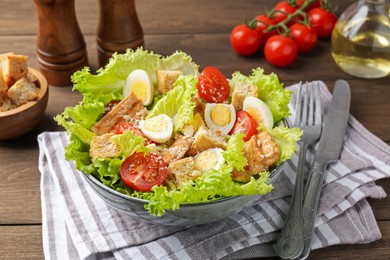 Photo of Delicious salad with croutons and ingredients on wooden table, closeup