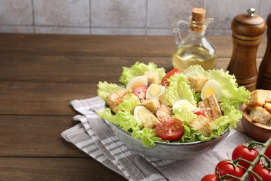 Photo of Delicious salad with croutons and ingredients on wooden table, closeup. Space for text