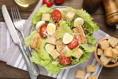 Photo of Delicious salad with croutons and ingredients on wooden table, flat lay