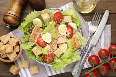 Photo of Delicious salad with croutons and ingredients on wooden table, flat lay