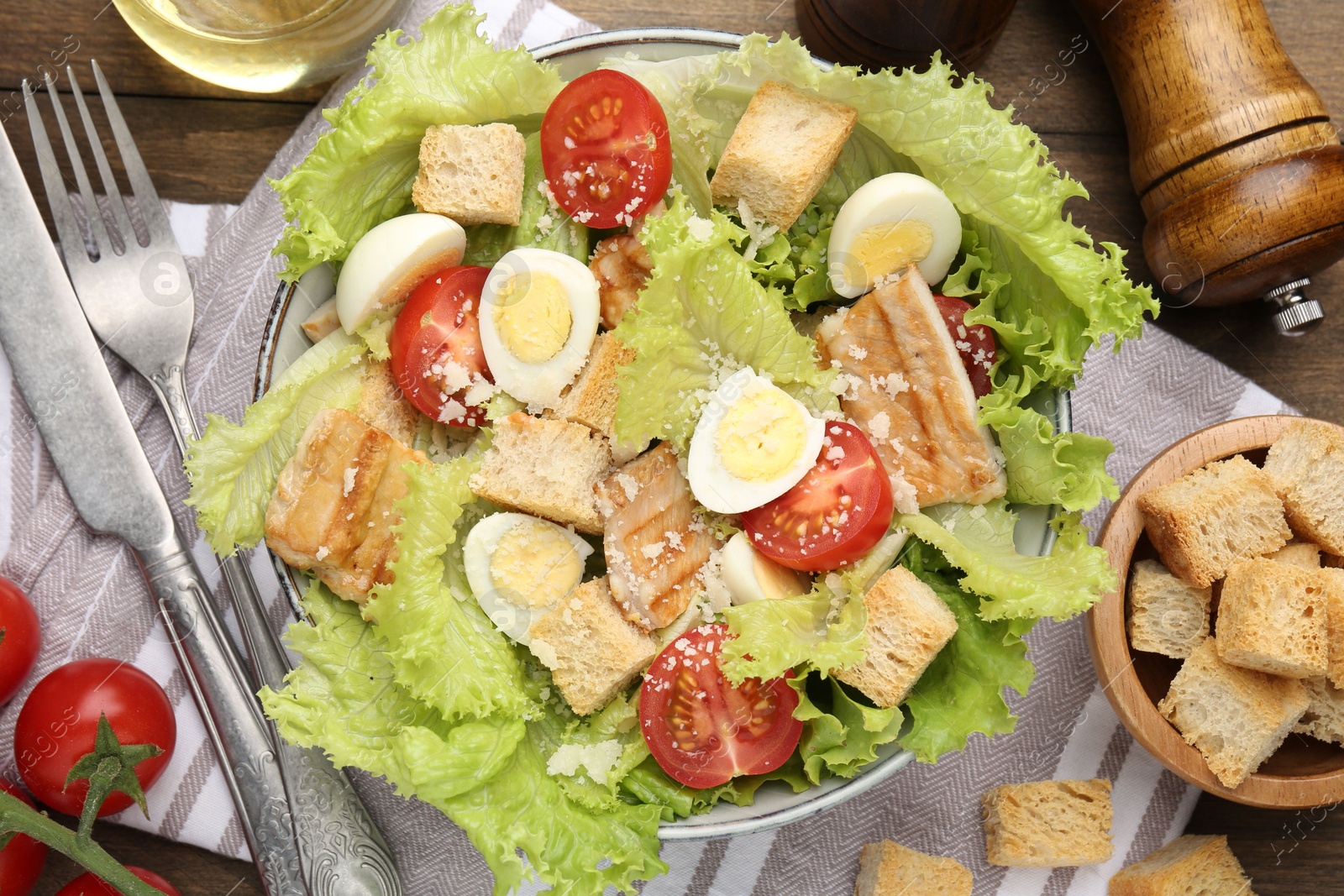 Photo of Delicious salad with croutons and ingredients on wooden table, flat lay