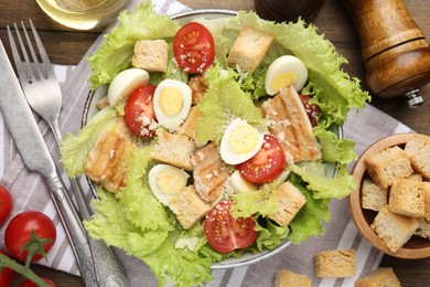 Photo of Delicious salad with croutons and ingredients on wooden table, flat lay