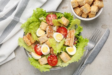 Photo of Delicious salad with croutons, chicken, quail eggs, tomato and cheese on grey table, flat lay