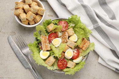 Photo of Delicious salad with croutons, chicken, quail eggs, tomato and cheese on grey table, flat lay