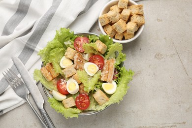 Photo of Delicious salad with croutons, chicken, quail eggs, tomato and cheese on grey table, flat lay