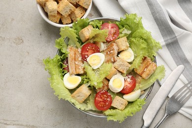 Photo of Delicious salad with croutons, chicken, quail eggs, tomato and cheese on grey table, flat lay