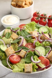 Photo of Delicious salad with croutons and vegetables served on light grey table, closeup