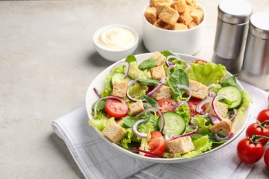 Photo of Delicious salad with croutons and vegetables served on light grey table, closeup. Space for text