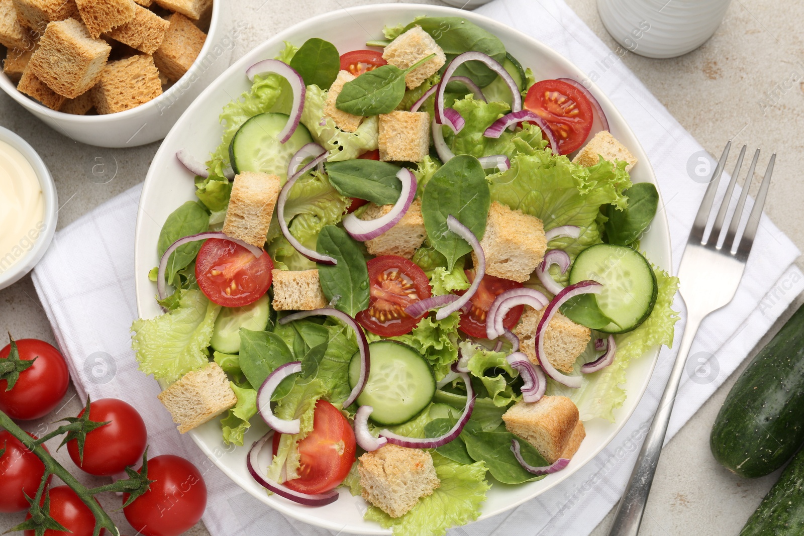Photo of Delicious salad with croutons and vegetables served on light grey table, flat lay