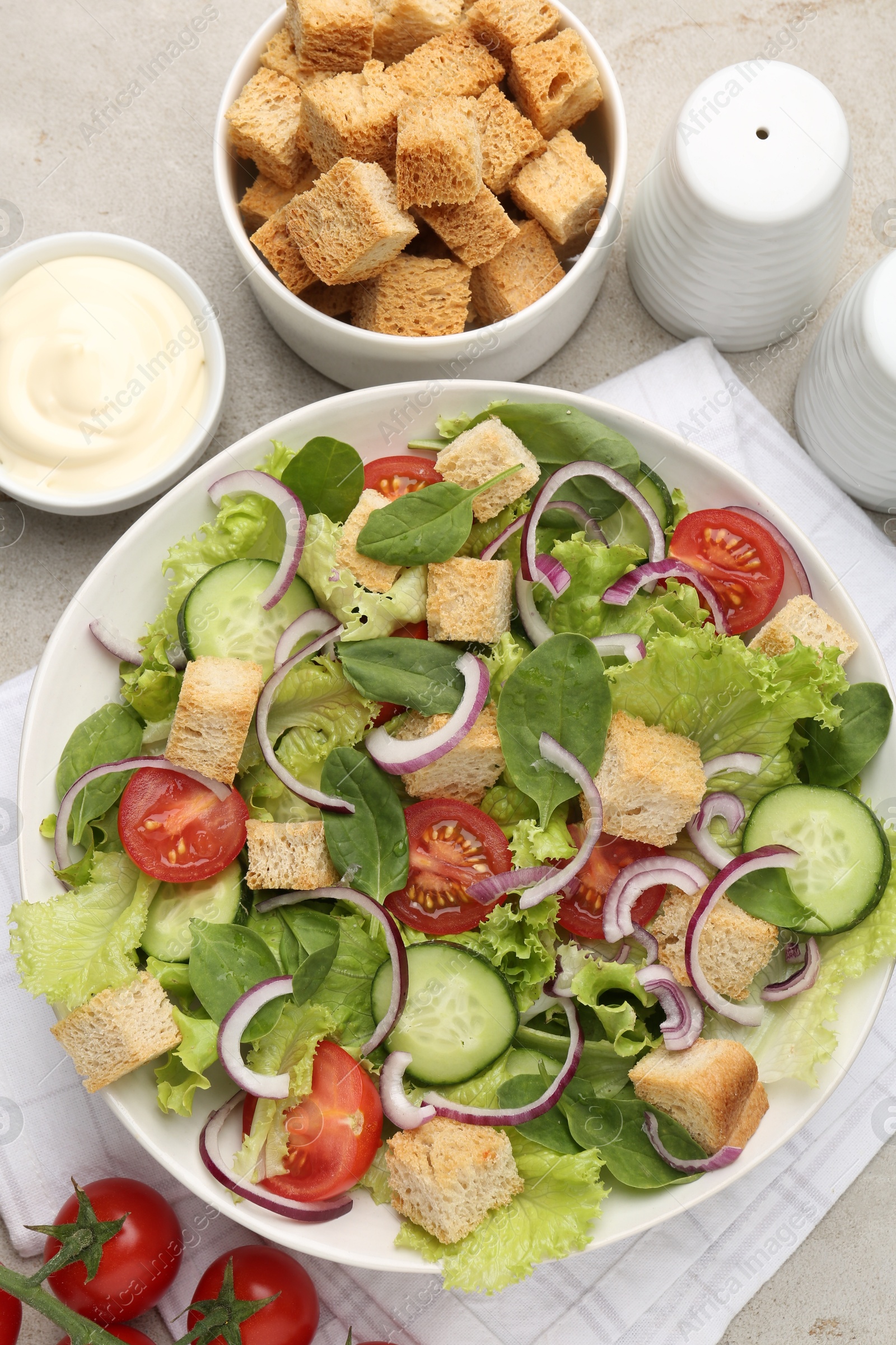 Photo of Delicious salad with croutons and vegetables served on light grey table, flat lay