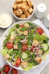 Photo of Delicious salad with croutons and vegetables served on light grey table, flat lay