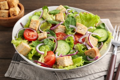 Photo of Delicious salad with croutons and vegetables served on wooden table, closeup