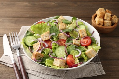 Photo of Delicious salad with croutons and vegetables served on wooden table, closeup