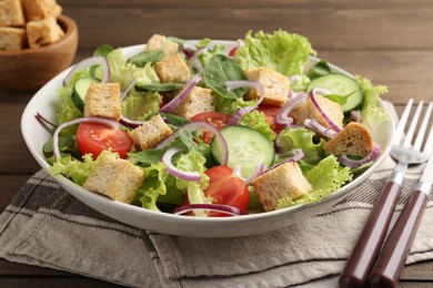 Photo of Delicious salad with croutons and vegetables served on wooden table, closeup