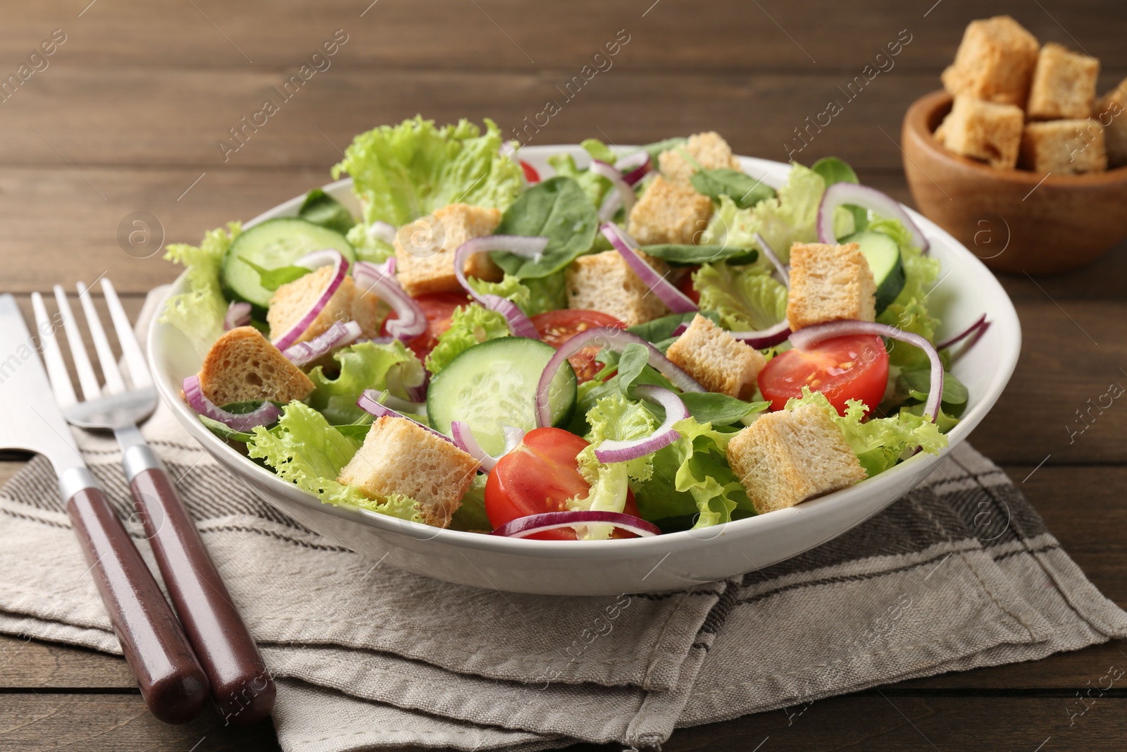 Photo of Delicious salad with croutons and vegetables served on wooden table, closeup