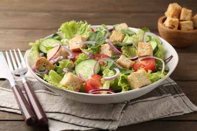 Photo of Delicious salad with croutons and vegetables served on wooden table, closeup