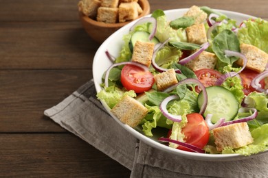 Photo of Delicious salad with croutons and vegetables on wooden table, closeup. Space for text