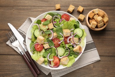 Photo of Delicious salad with croutons and vegetables on wooden table, flat lay