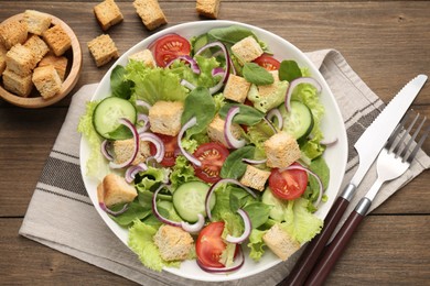 Photo of Delicious salad with croutons and vegetables on wooden table, flat lay