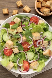 Photo of Delicious salad with croutons and vegetables on wooden table, flat lay
