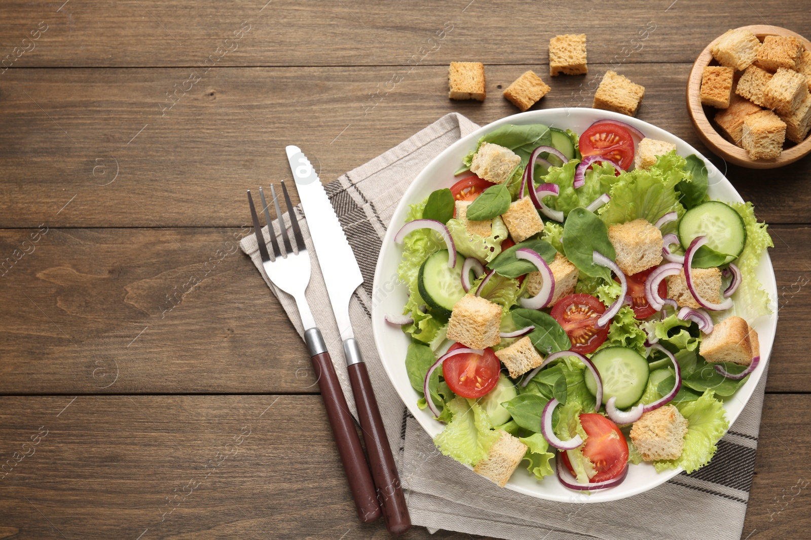 Photo of Delicious salad with croutons and vegetables on wooden table, flat lay. Space for text