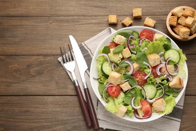 Photo of Delicious salad with croutons and vegetables on wooden table, flat lay. Space for text