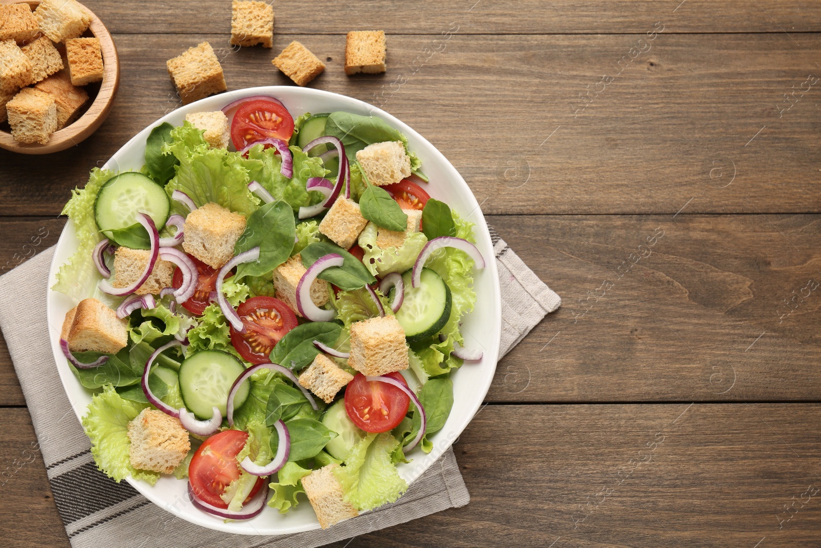 Photo of Delicious salad with croutons and vegetables on wooden table, flat lay. Space for text