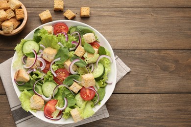 Photo of Delicious salad with croutons and vegetables on wooden table, flat lay. Space for text