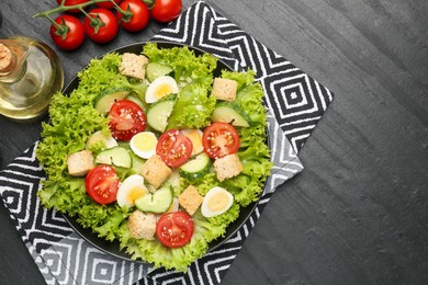 Photo of Delicious salad with croutons and ingredients on black table, flat lay. Space for text