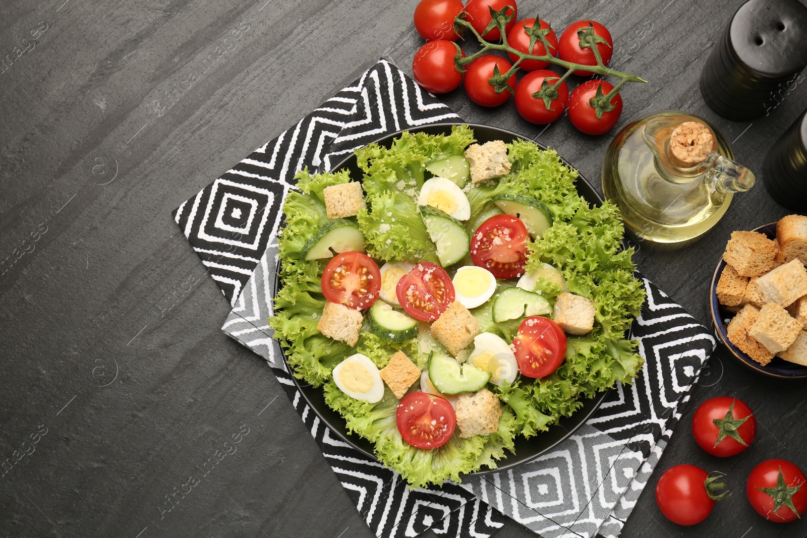 Photo of Delicious salad with croutons and ingredients on black table, flat lay. Space for text